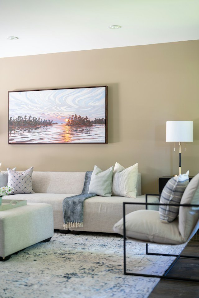 A modern living room featuring cream walls, chocolate-brown wood, olive-green cushions, and rust-colored accents.