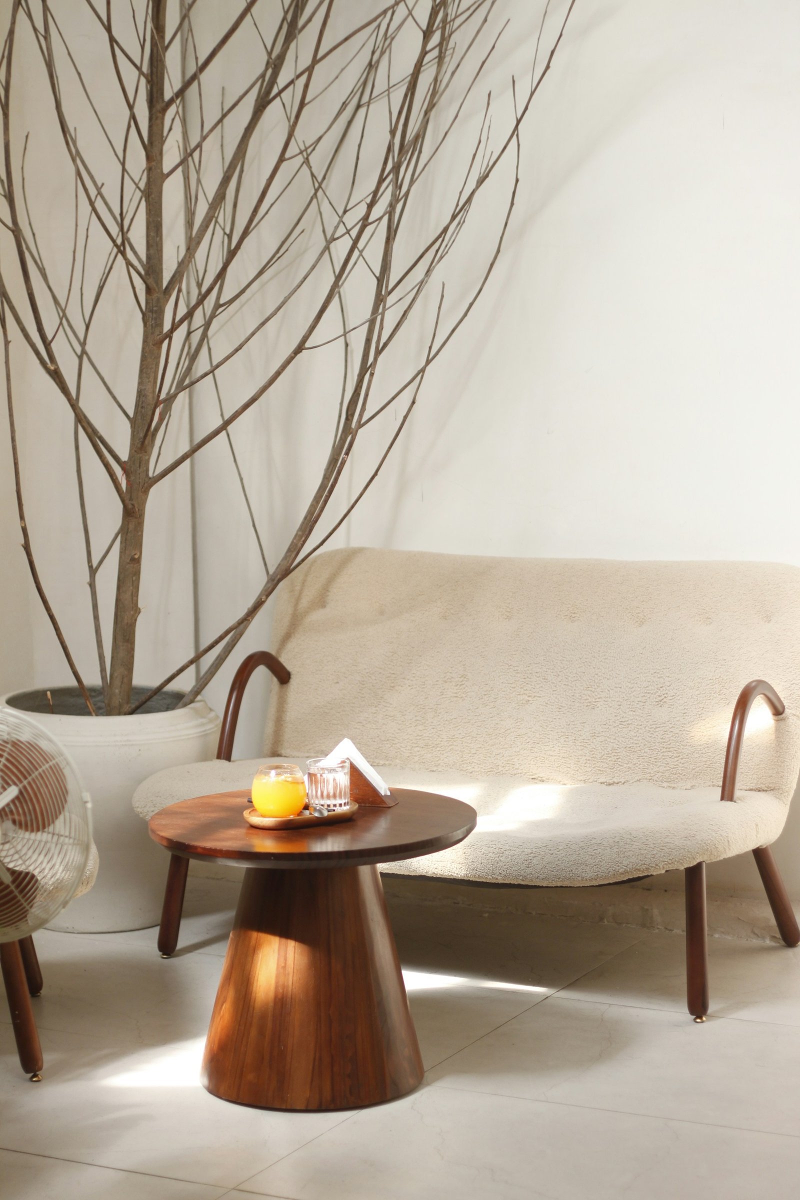 A warm interior featuring a linen sofa, natural wooden furniture, a woven rug, handmade ceramic vases, and soft daylight.